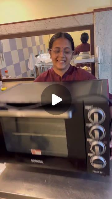 A teacher at Anantha Academy smiling behind a small oven during the baking session